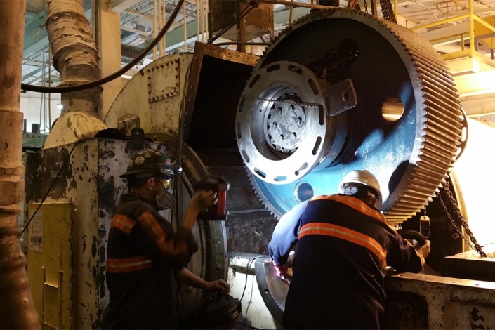 Men examining large gear on site